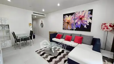 Modern living room with stylish decor, featuring a sectional sofa, glass coffee table, and vibrant wall art.