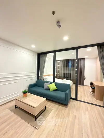 Modern living room with stylish decor and glass partition leading to bedroom