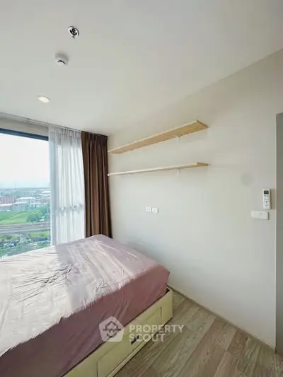 Bright bedroom with large window and wooden shelves, offering a serene view.