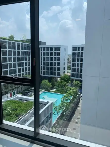 Modern apartment complex with pool view from window, showcasing urban living and luxury amenities.