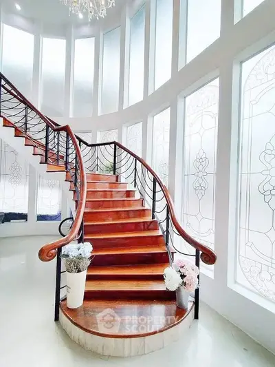 Elegant spiral staircase with wooden steps and decorative railing in a luxurious home interior.