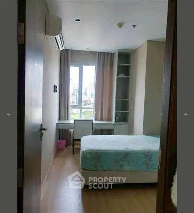 Cozy bedroom with city view, featuring a bed, desk, and built-in shelves, perfect for urban living.