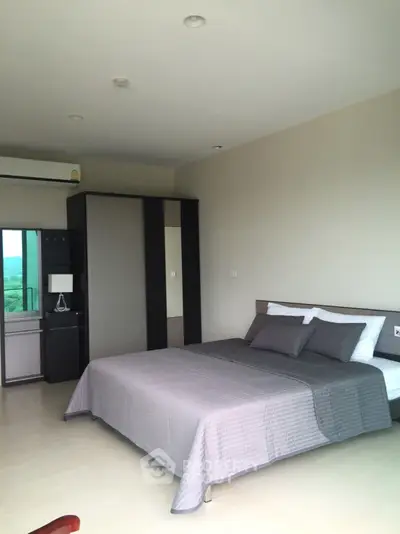 Spacious bedroom with modern design, large bed, and ample natural light from sliding glass doors leading to a balcony with a serene view.
