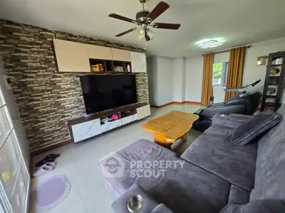 Spacious living room with modern decor and large TV, perfect for relaxation.