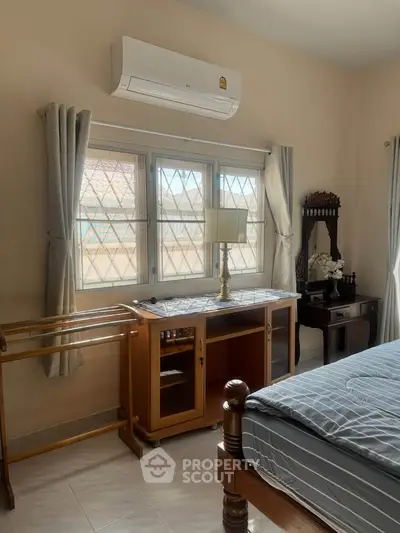 Cozy bedroom with air conditioning and natural light, featuring elegant wooden furniture and stylish decor.