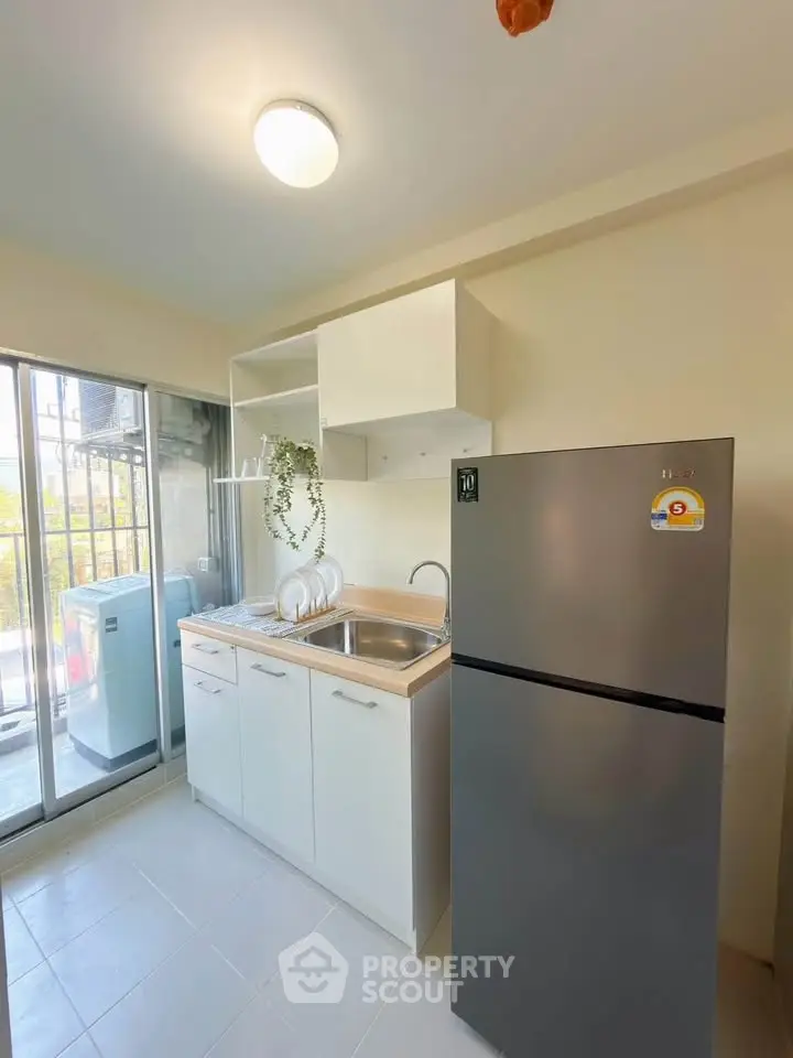 Modern kitchen with sleek fridge and compact design, perfect for urban living.