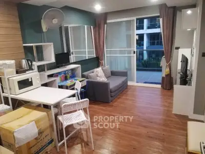 Modern living room with wooden flooring and sliding glass doors leading to a balcony.