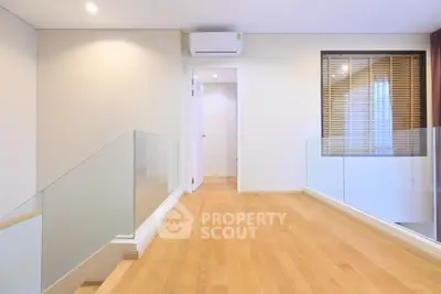 Modern hallway with wooden flooring and glass railing in a contemporary home.