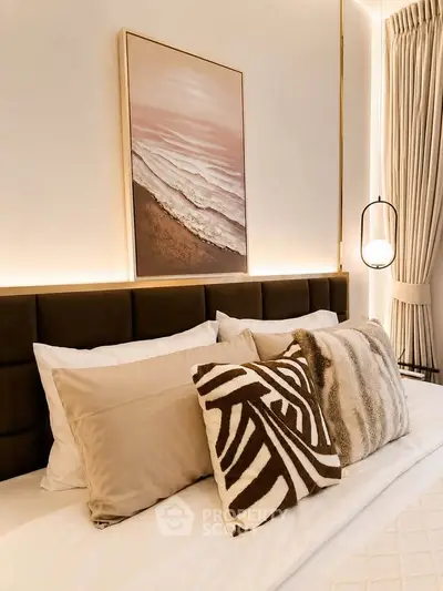 Luxurious bedroom with elegant decor and stylish cushions, featuring a serene ocean artwork above the bed.