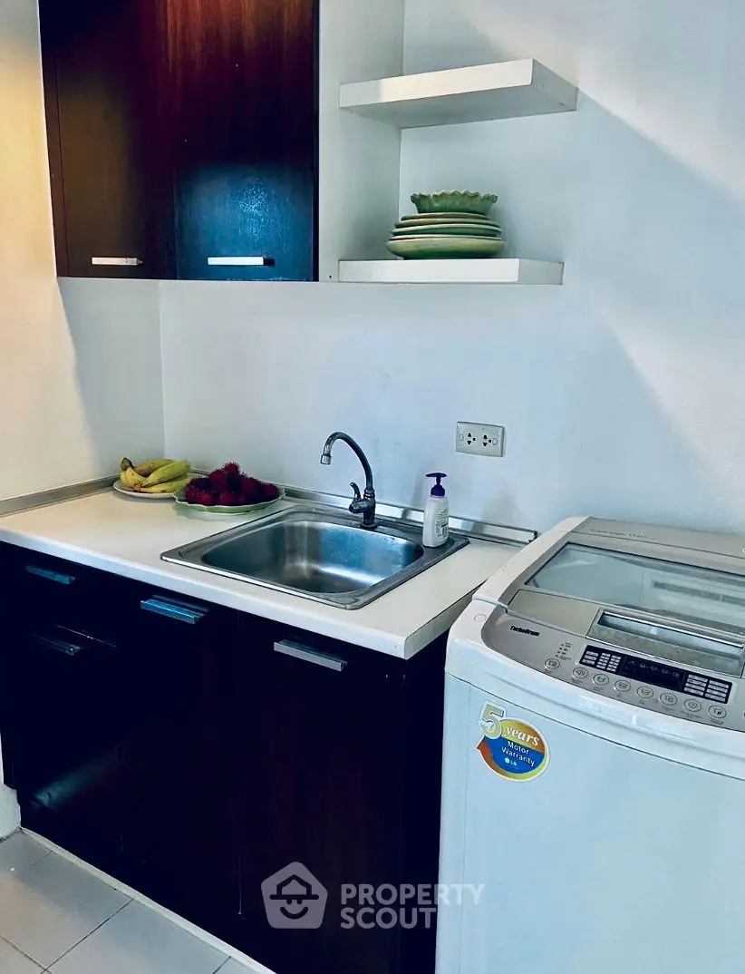 Compact kitchen with washing machine and sleek cabinetry, perfect for modern living.