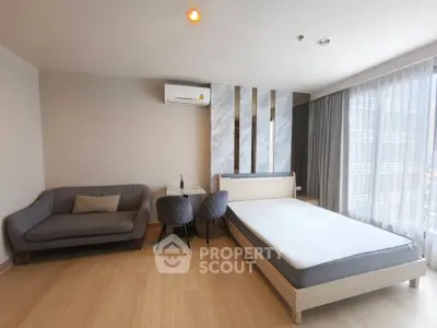 Modern studio apartment with stylish decor, featuring a cozy bed, chic sofa, and elegant dining area.