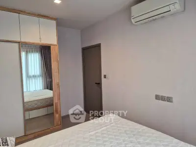 Modern bedroom with mirrored wardrobe and air conditioning unit