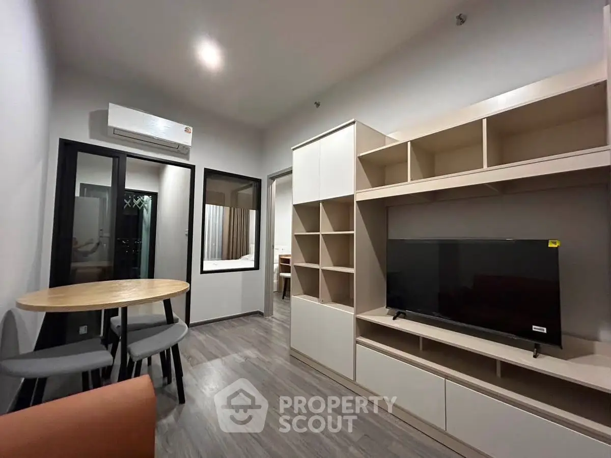 Modern living room with sleek furniture and wall-mounted TV in a cozy apartment setting.