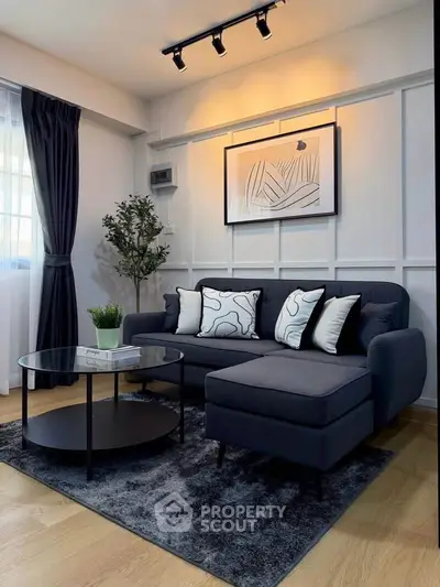 Stylish modern living room with dark sofa, chic decor, and elegant lighting.