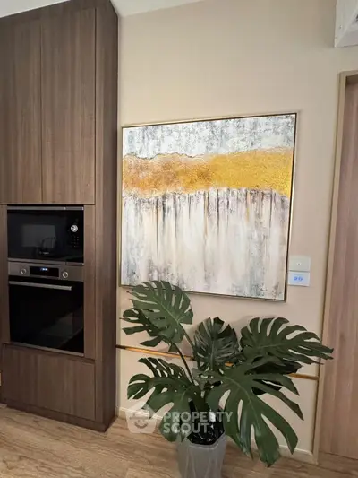 Modern kitchen interior with built-in oven and stylish wall art, featuring a lush indoor plant for a cozy ambiance.