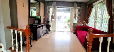 Spacious living room with large windows and balcony access, featuring elegant decor and natural light.