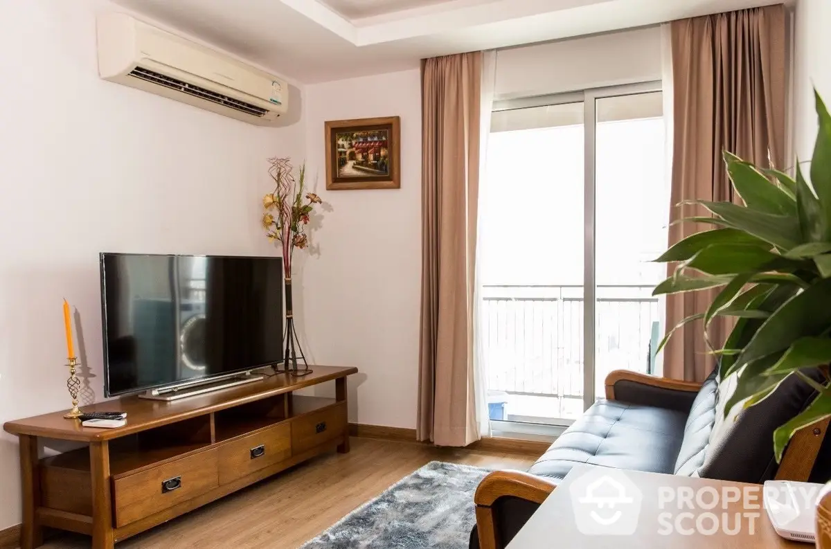 Cozy living room with modern furnishings, ample natural light, and balcony access, perfect for relaxation and entertainment.