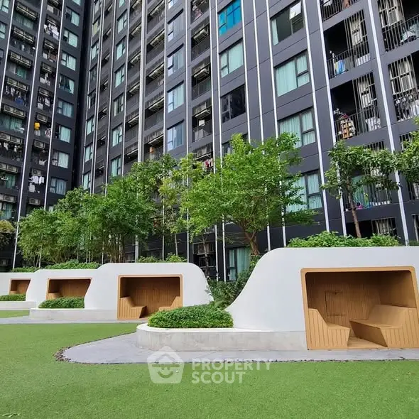 Modern residential building with lush green garden and unique seating areas.