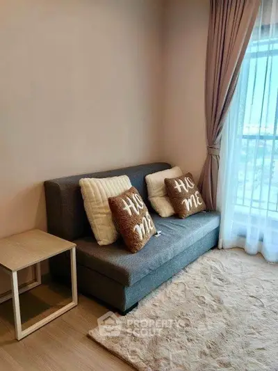 Cozy living room with sofa, decorative pillows, and large window with curtains.