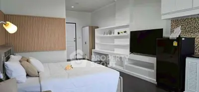 Modern studio apartment with sleek design, featuring a cozy bed, TV, and stylish shelving.