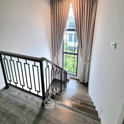 Elegant staircase with modern railing and large window view