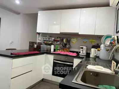 Modern kitchen with sleek white cabinets and black countertops, featuring built-in oven and ample storage space.