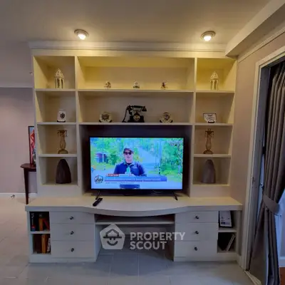 Spacious living room with built-in shelving and modern TV setup, perfect for entertainment.