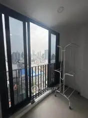 Modern apartment balcony with city skyline view and drying rack.