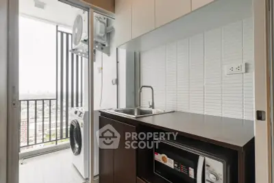 Modern kitchen with balcony view, featuring washing machine and microwave, ideal for urban living.
