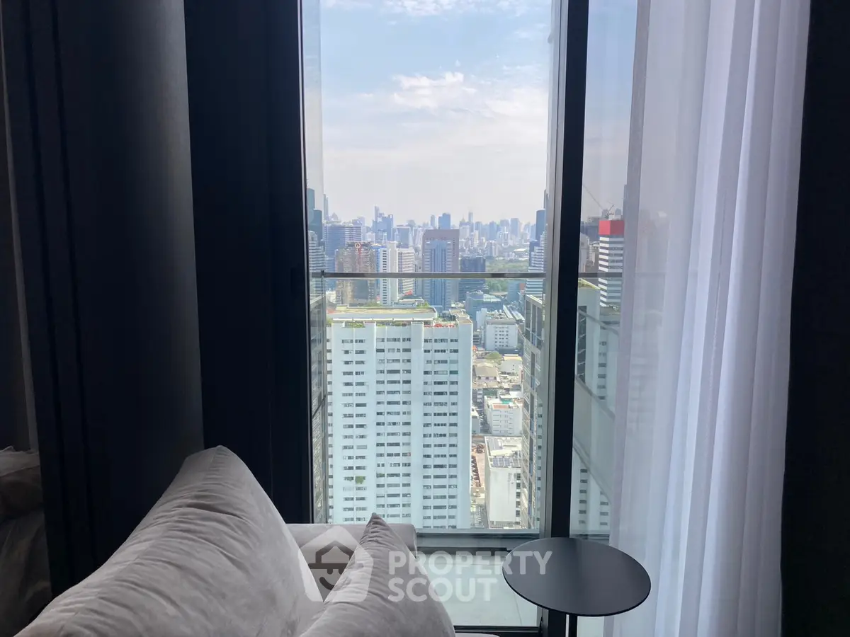 Stunning city view from modern apartment living room with large windows and cozy seating.