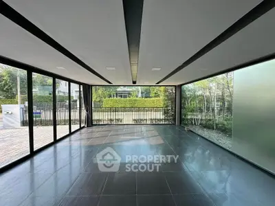 Spacious modern room with floor-to-ceiling windows and garden view, perfect for versatile living space.