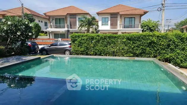 Stunning residential pool with lush greenery and modern houses in the background.