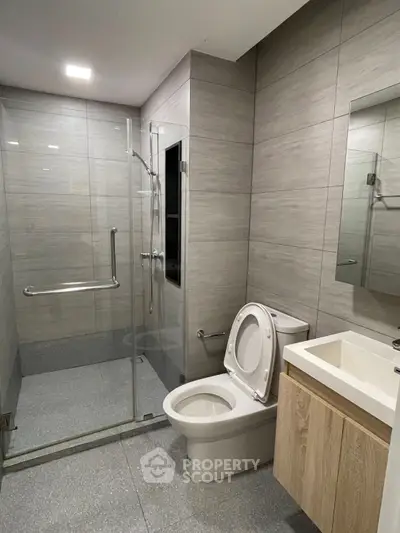 Modern bathroom with glass shower and sleek fixtures in contemporary apartment.