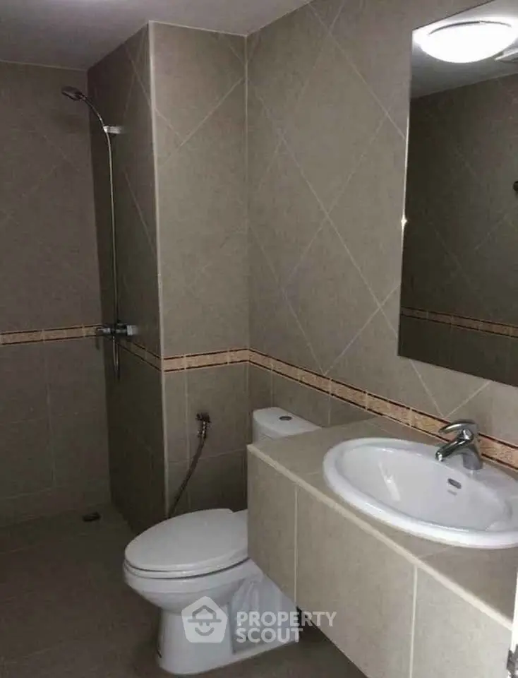 Modern bathroom with sleek fixtures and neutral tiles, featuring a shower and a stylish sink.
