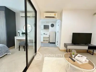 Modern open-plan living room with sleek decor and glass partition to bedroom.