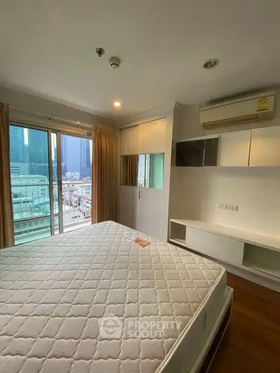 Modern bedroom with city view, featuring large windows and built-in storage, perfect for urban living.