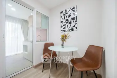 Modern dining area with stylish chairs and glass table adjacent to a sleek kitchen.