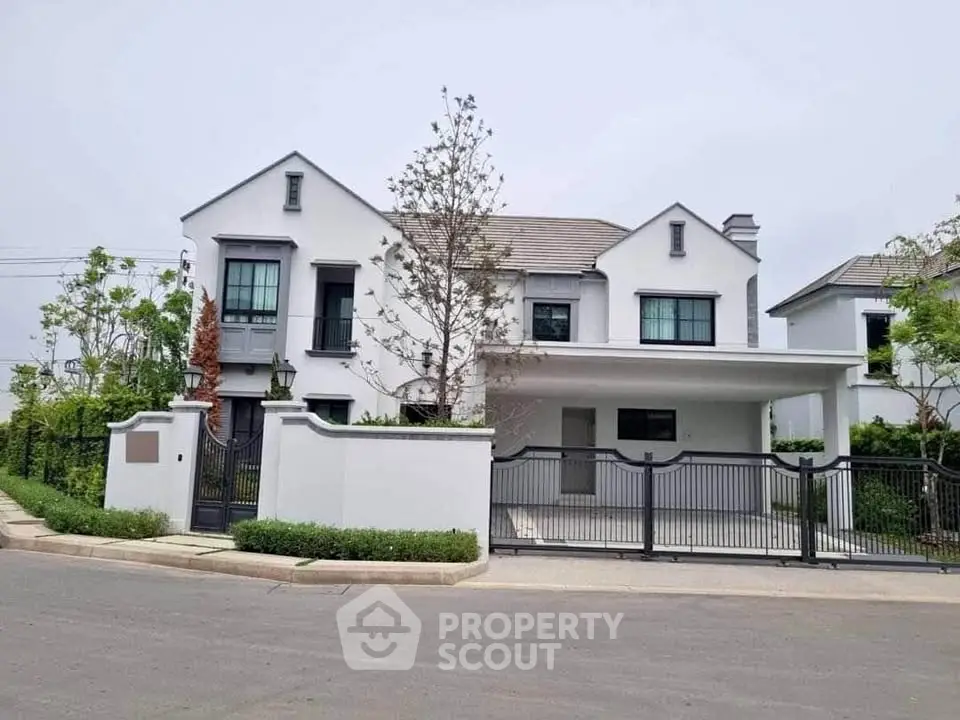 Elegant modern house with gated entrance and lush greenery in a serene neighborhood.