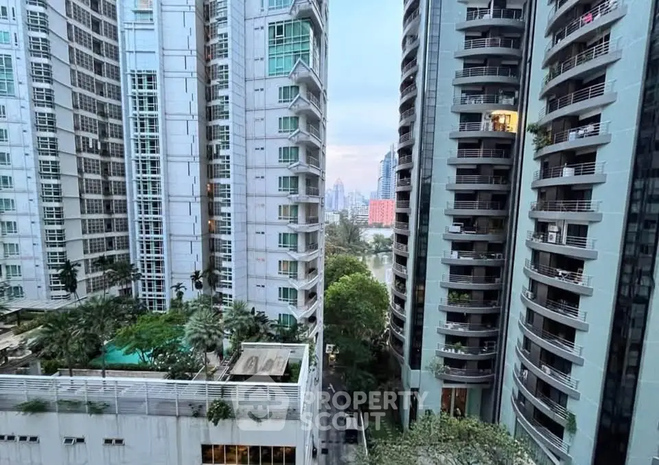 Stunning urban view from high-rise apartment with lush greenery and modern architecture.