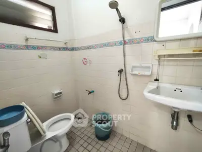 Spacious bathroom with shower, toilet, and sink in a tiled setting.