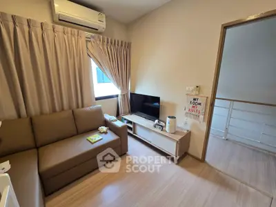 Cozy living room with modern sofa, TV, and air conditioning in a stylish apartment.