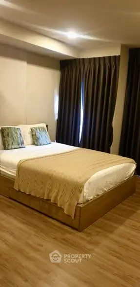 Cozy bedroom with elegant decor and wooden flooring, featuring a comfortable bed and stylish curtains.