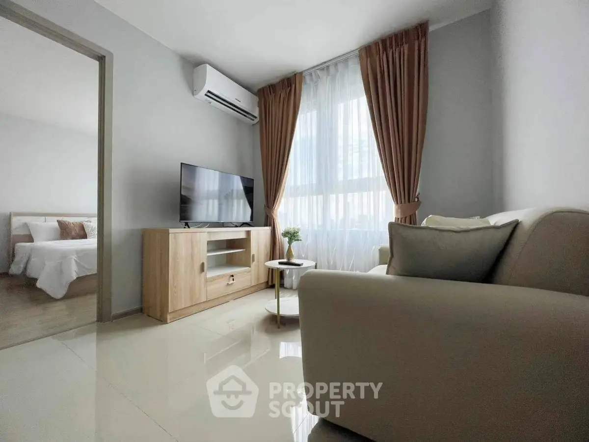 Modern living room with sleek furniture and natural light, adjacent to a cozy bedroom.