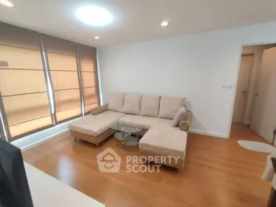 Spacious living room with modern beige sectional sofa and wooden flooring