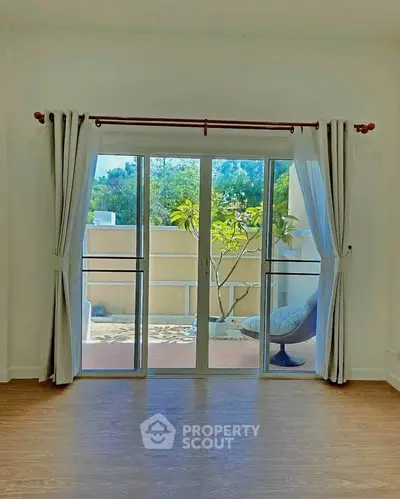Bright living room with sliding glass doors leading to a cozy balcony with outdoor seating.