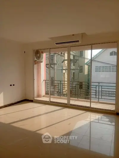 Spacious empty living room with large windows and balcony access, perfect for natural light lovers.