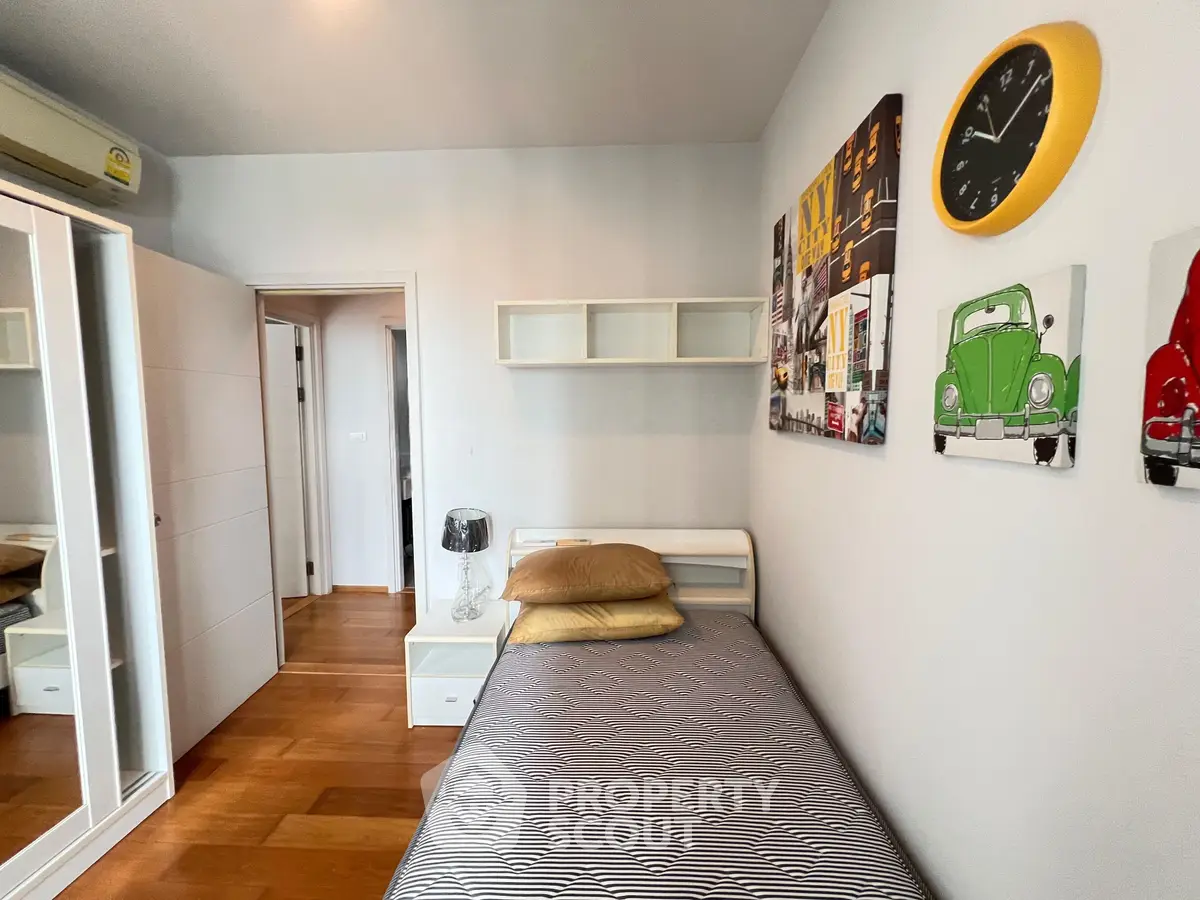 Cozy bedroom with modern decor, featuring a single bed, wall art, and wooden flooring.