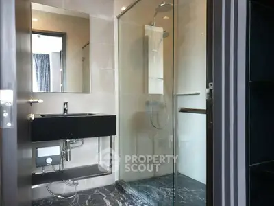 Modern bathroom with sleek glass shower and stylish black sink in contemporary apartment.