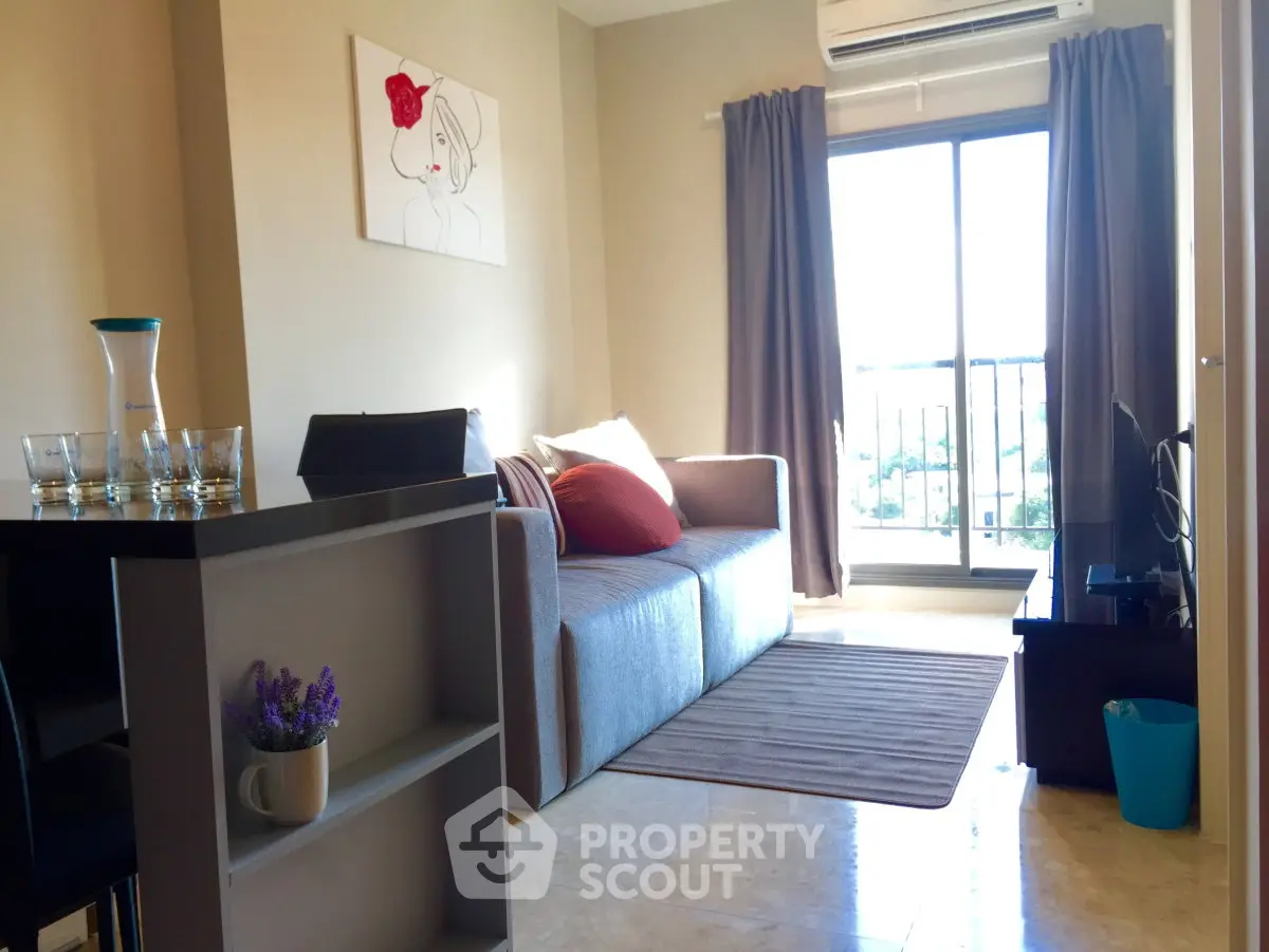 Charming living room with modern decor and natural light, featuring a cozy sofa and balcony access.