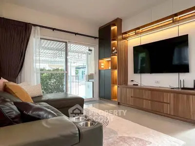 Modern living room with sleek furniture and large TV, featuring a cozy ambiance and natural light from sliding doors.